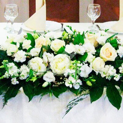 Цветочная композиция на стол молодожёнов в белом цвете с кремовыми розами