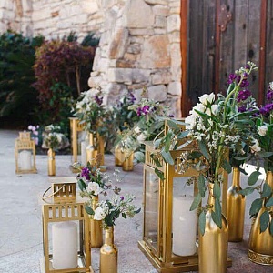 Украшение свадьбы цветами в золотых бутылках и фонарями