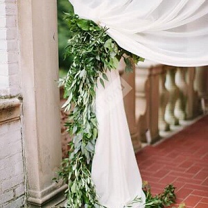 Оформление свадьбы белой тканью и зелеными листьями