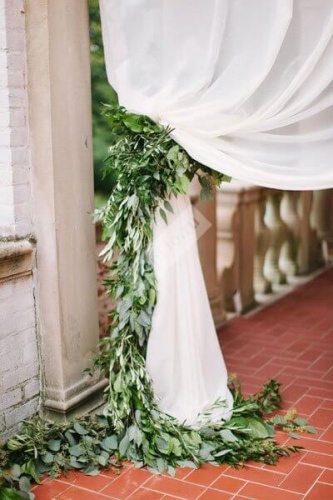 Оформление свадьбы белой тканью и зелеными листьями