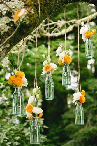 Украшение подвешенными бутылками с цветами в бело оранжевых тонах