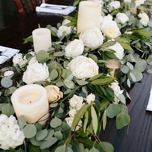 Украшение стола белыми цветами и зелеными листьями