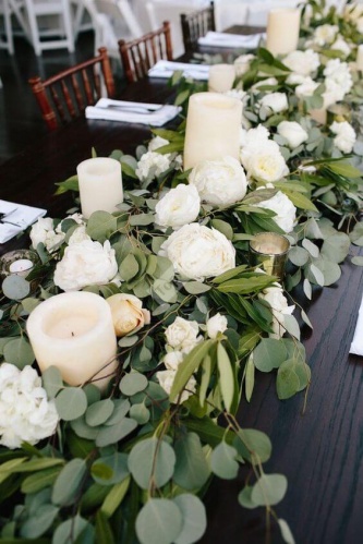 Украшение стола белыми цветами и зелеными листьями